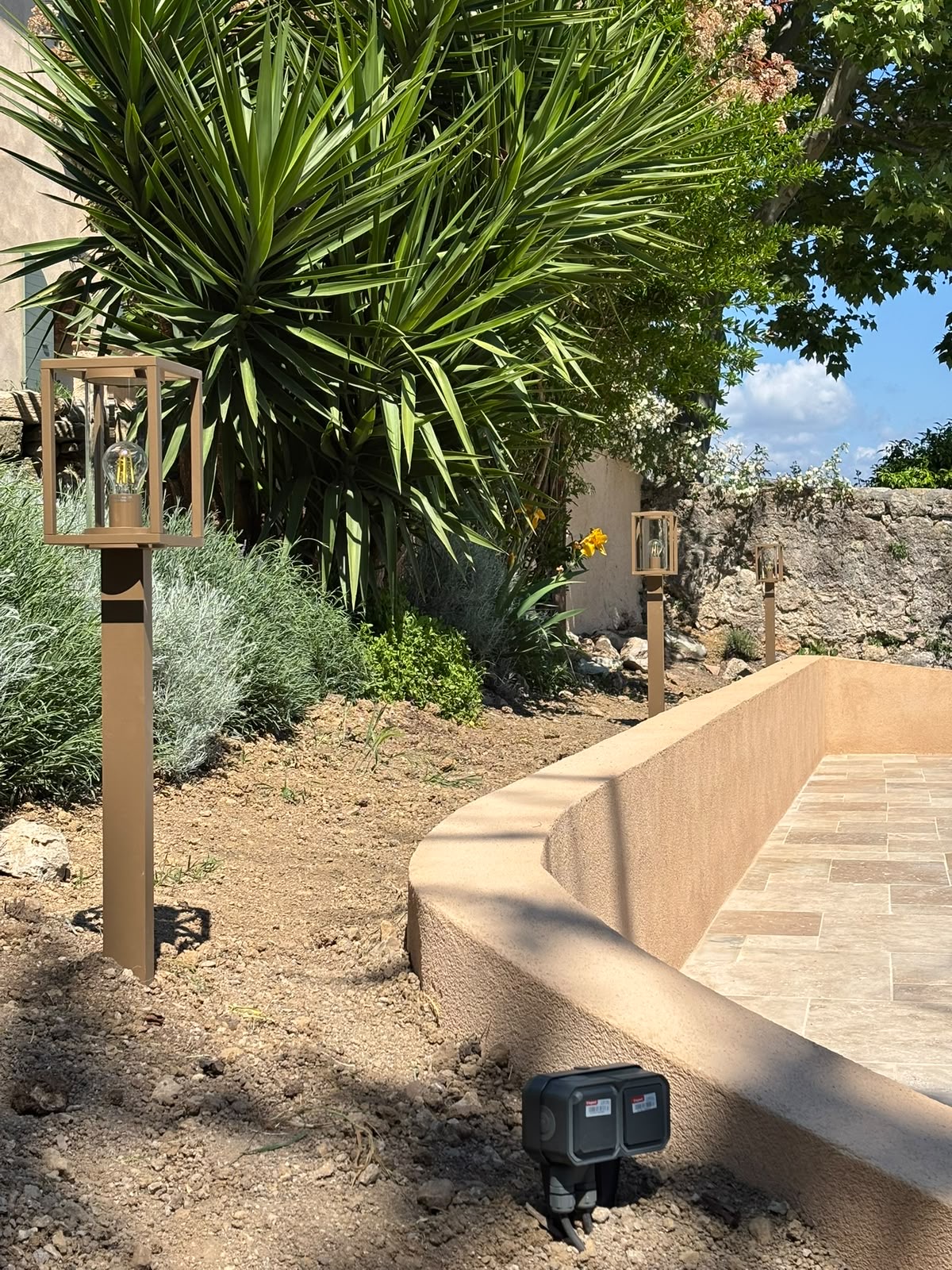 Bornes lanternes laiton installées dans un jardin méditerranéen de jour, Var